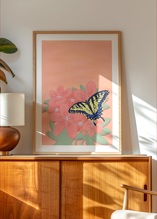 ein gerahmtes Gemälde eines Schmetterlings auf einer rosa Blume, ausgestellt auf einem Holzschrank oder Regal.