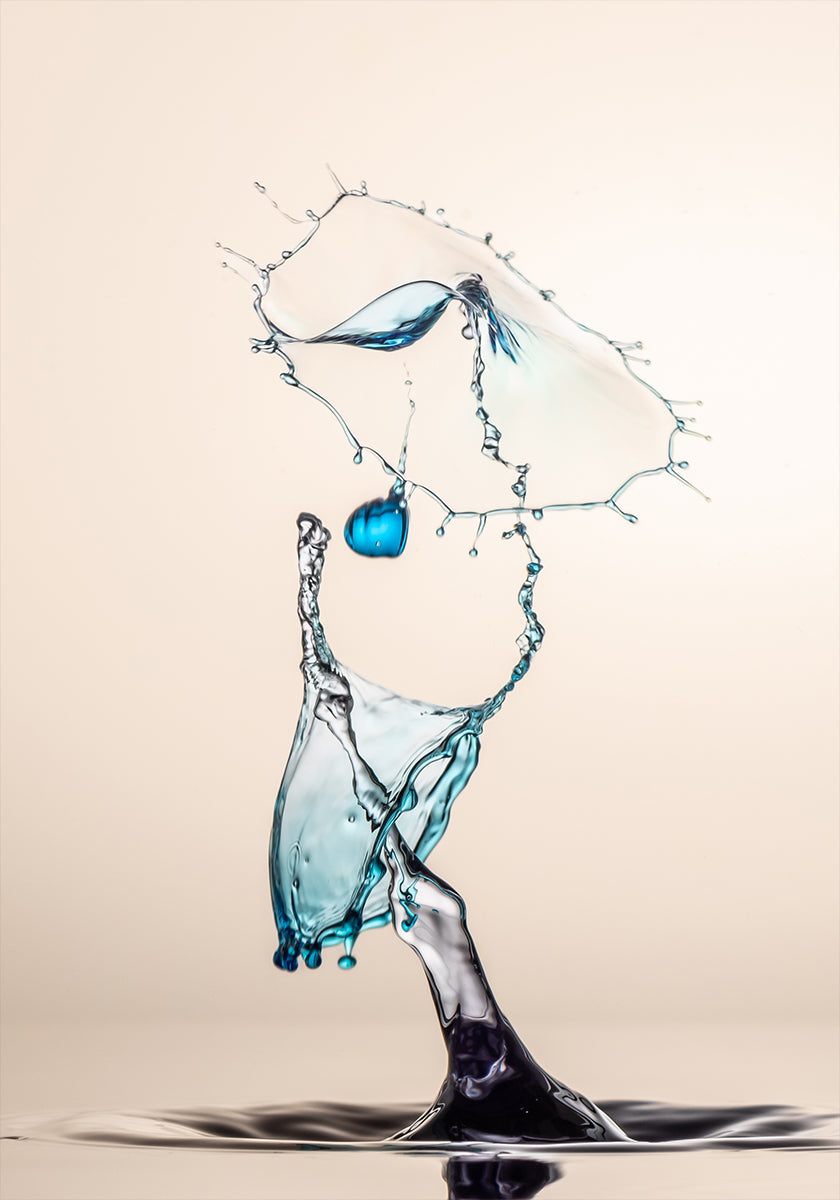 ein dynamischer Wasserspritzer mit einem blauen Objekt, das in der Luft schwebt, und einem großen Wasserspritzer, der herabstürzt und ein Gefühl von Bewegung und Energie erzeugt.